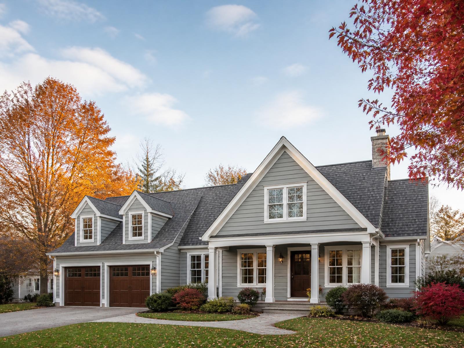 New England suburban home with a gray asphalt shingle roof on an autumn afternoon